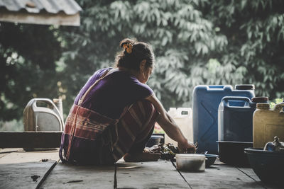 Woman preparing food while sitting outdoors