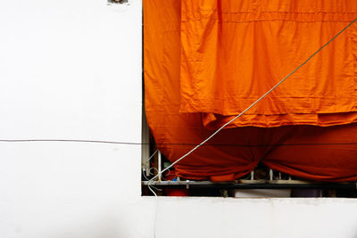 Orange robe drying on window