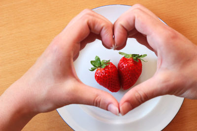 Midsection of woman holding strawberries on table