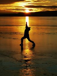 Silhouette man on beach against sky during sunset