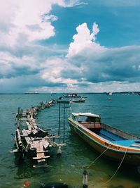 Boats in sea against cloudy sky