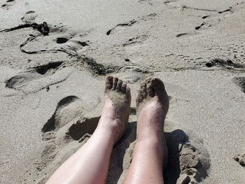 Low section of woman on sand at beach