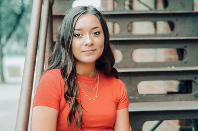 Portrait of smiling young woman sitting on staircase outdoors