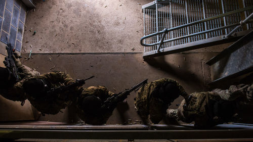 Directly above shot of army soldiers with rifles in abandoned building