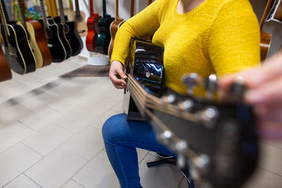 Midsection of woman holding camera while sitting on seat