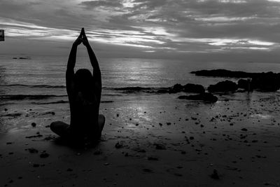 Silhouette person on beach against sky during sunset