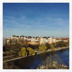 River by cityscape against blue sky