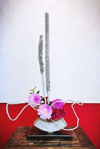 Close-up of white flowers in vase on table against wall