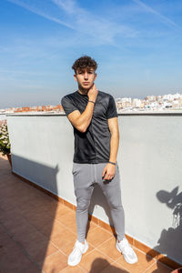 Full length of young man looking at camera against sky
