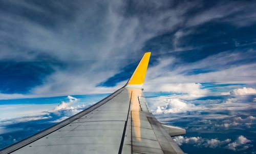 Low angle view of airplane wing against cloudy sky