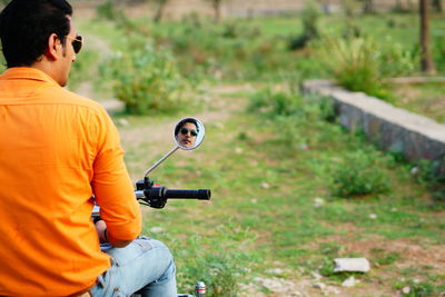 Rear view of mid adult man reflecting on side-view mirror