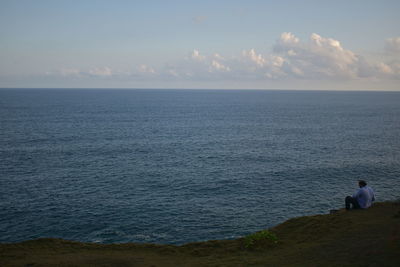 Rear view of man looking at sea against sky