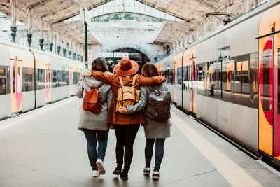 Rear view of friends walking at station