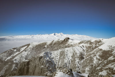 Scenic view of snowcapped mountains against clear blue sky