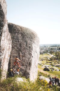 Man climbing on rock against sky