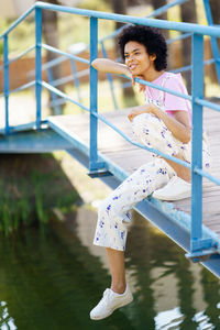 Portrait of young woman sitting on railing