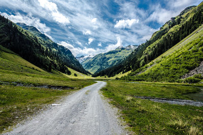 Road amidst green landscape against sky