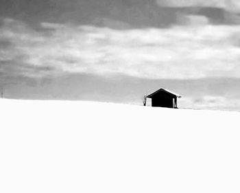 Snow covered landscape against cloudy sky