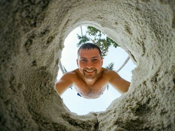 Portrait of shirtless man standing on rock