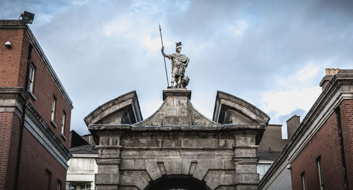 Low angle view of statue of historic building against sky