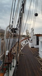 Sailboats moored at harbor against cloudy sky