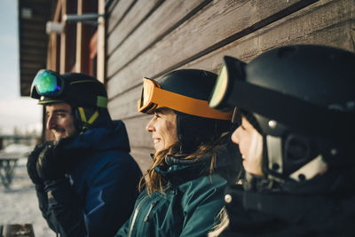 Smiling friends wearing sports helmets at ski resort during sunset