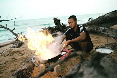 Young man on beach against sky