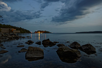 Rocks on beach against sky during sunset