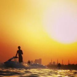 Woman jumping in water at sunset