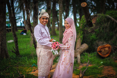 Portrait of smiling couple standing against trees