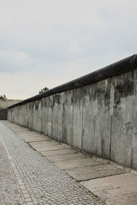 Footpath by wall against sky