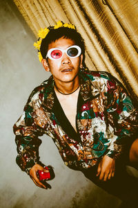 Portrait of young man looking away while sitting against wall