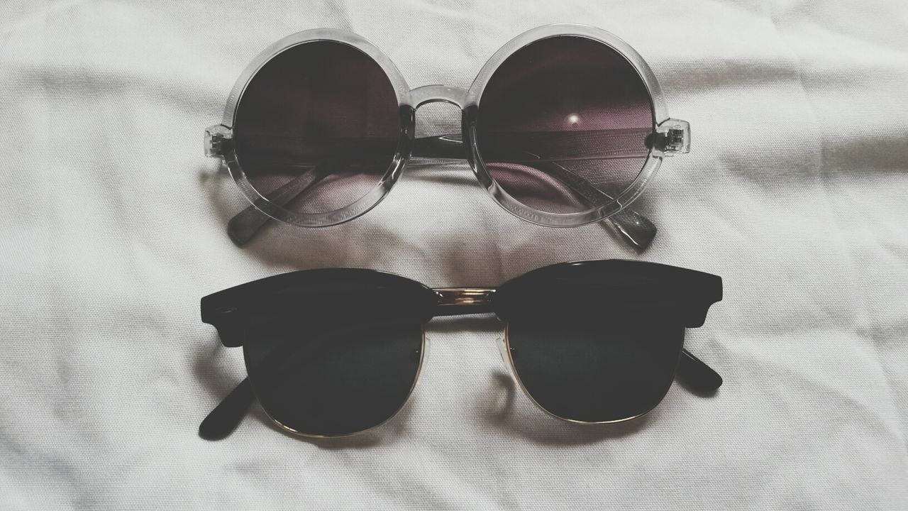 indoors, still life, table, close-up, no people, high angle view, single object, reflection, wall - building feature, man made object, black color, directly above, sunglasses, two objects, home interior, pattern, circle, simplicity, wood - material, day