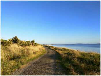 Narrow pathway and sea against clear blue sea