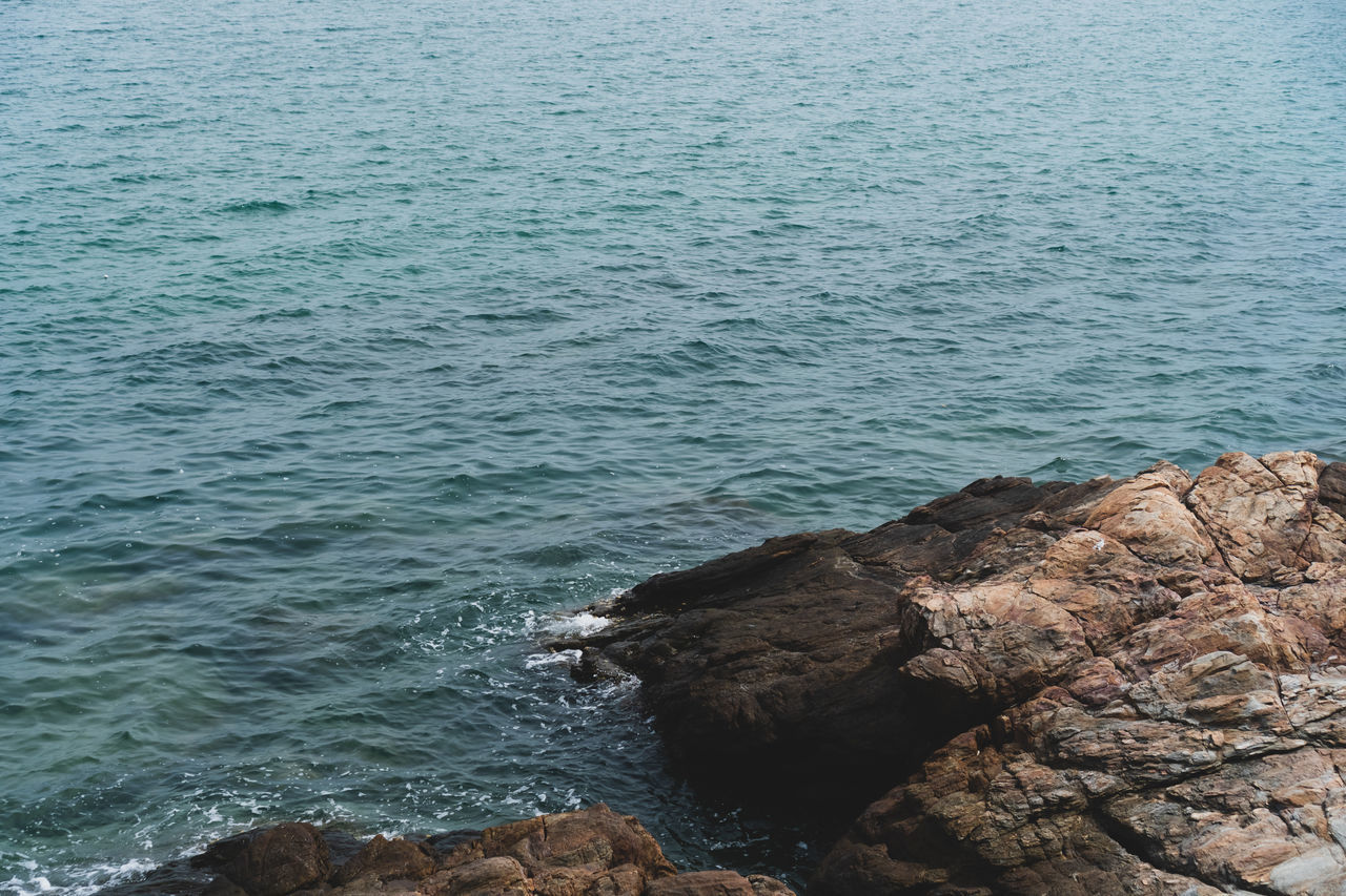 HIGH ANGLE VIEW OF ROCK FORMATIONS AT SEA