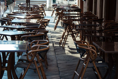 Empty chairs and tables in row at sidewalk cafe