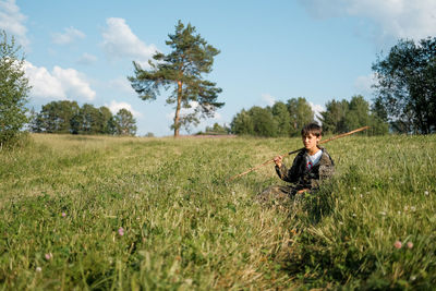 Man sitting on field against sky