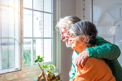 Woman looking through window at home