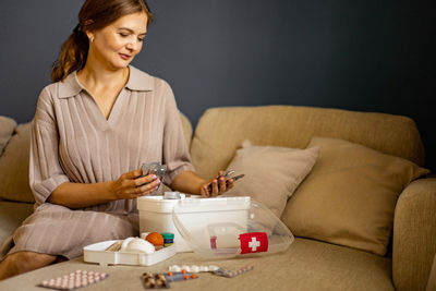 Young woman using mobile phone while sitting on sofa at home