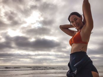 Low angle portrait of woman standing at beach