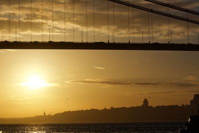 Low angle view of bridge over river against sky during sunset