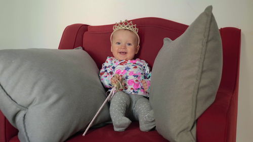 Cute baby girl sitting on sofa at home