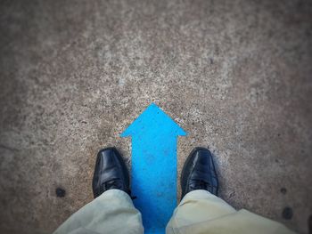 High angle view of man standing on arrow symbol