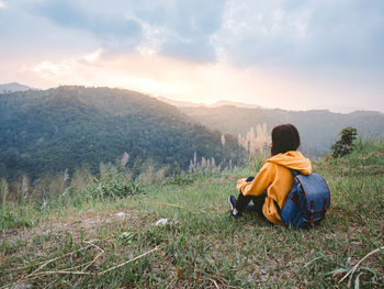 Rear view of woman sitting on land against sky