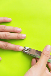 Close-up of person cutting fingernails over green background