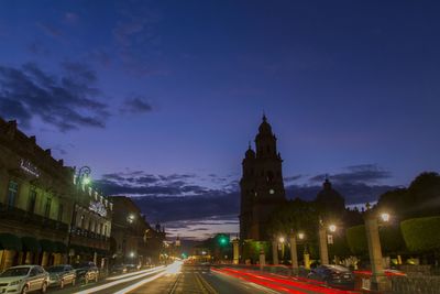 Light trails on street amidst buildings at night