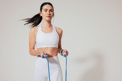 Portrait of young woman standing against white background