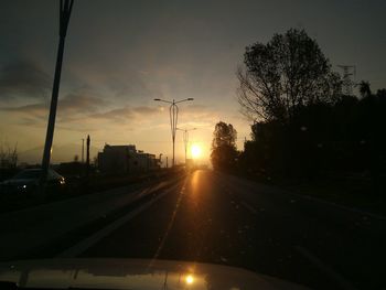 Cars on road against sky during sunset