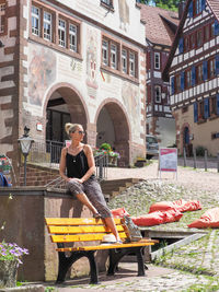 Woman sitting on seat against buildings