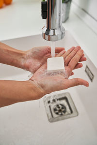 Woman washing her hands on the kitchen sink to avoid possible infection